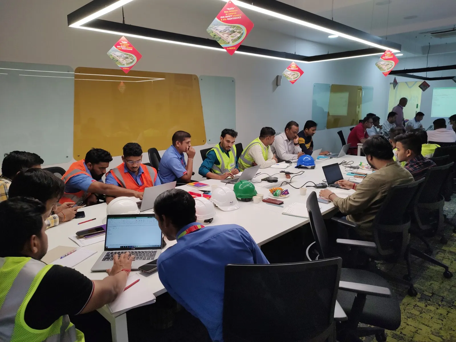 Long conference table of manufacturing employees in safety vests during training